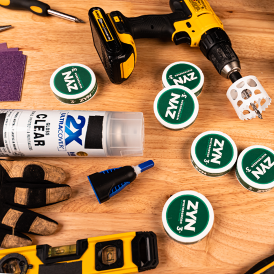 Wintergreen ZYN cans on a wooden table surrounded by tools.