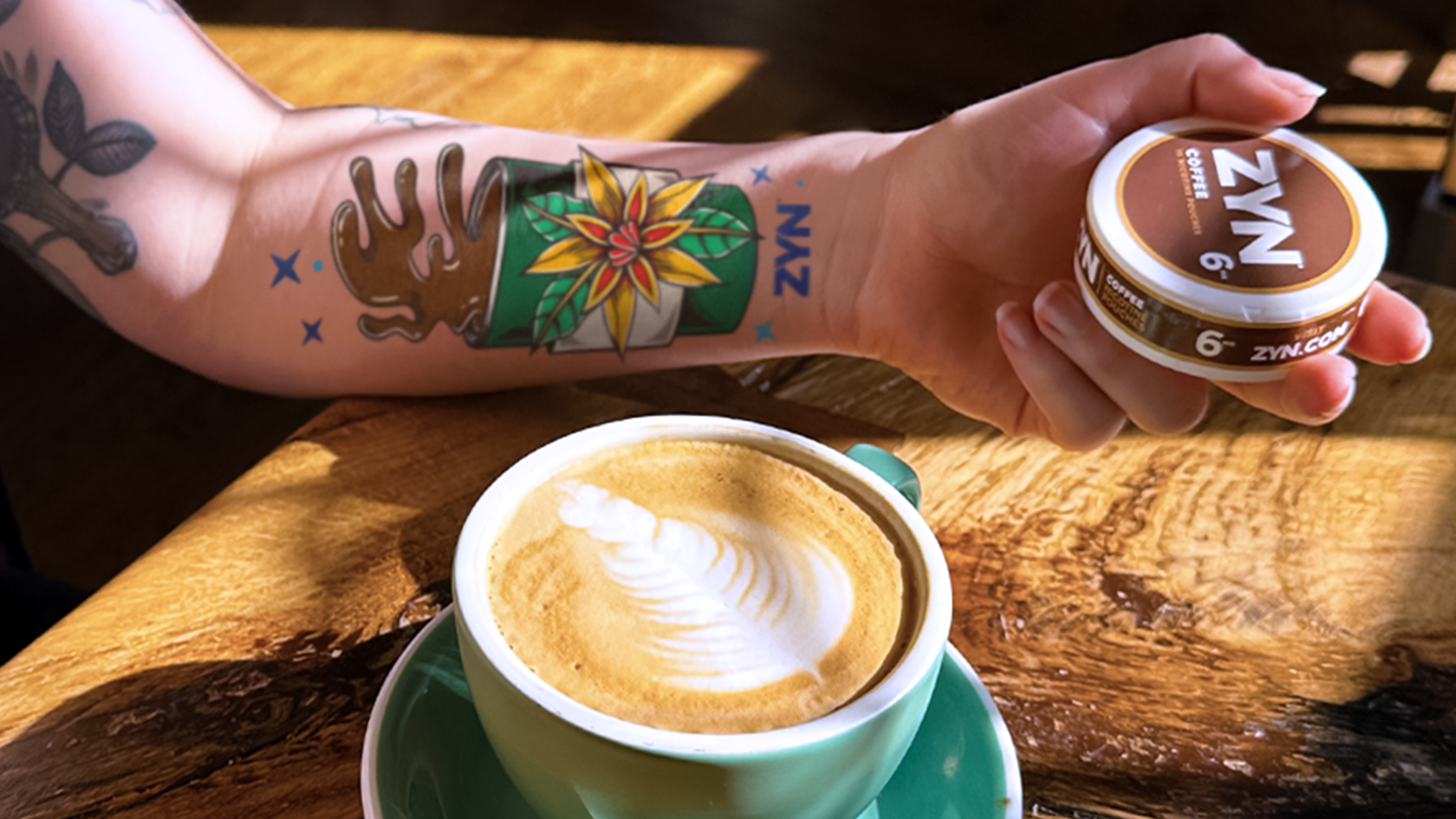 An artisan coffee next to woman's arm with ZYN tattoo