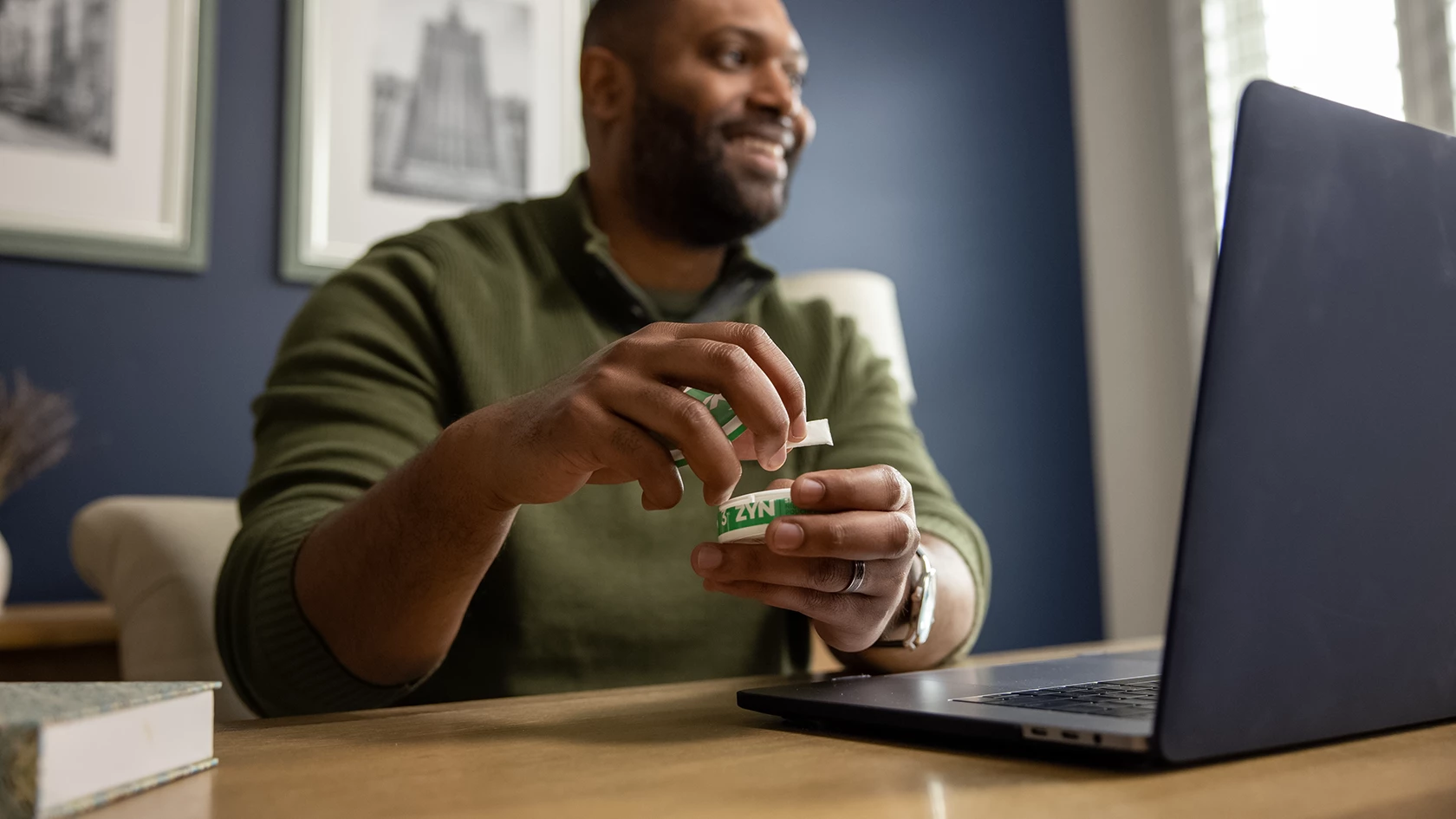 A man consuming ZYN spearmint while browsing on his laptop.