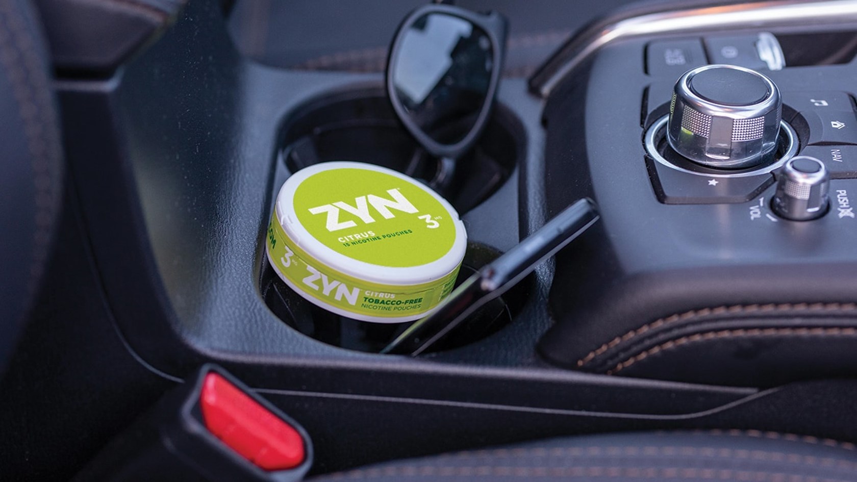 A can of Citrus ZYN Tobacco-Free Nicotine Pouches in a car cup holder.