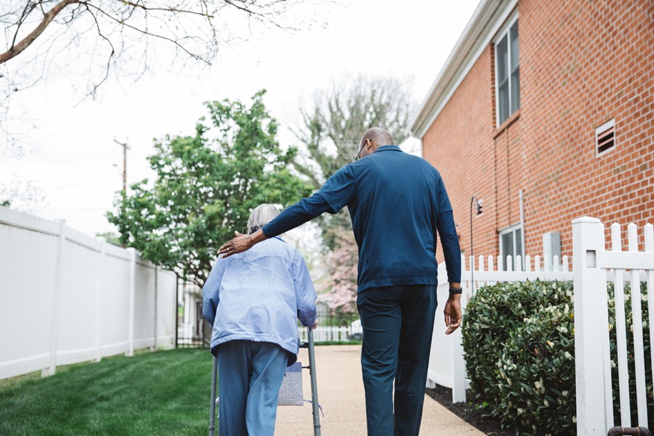 Man Assisting a Woman with a Walker